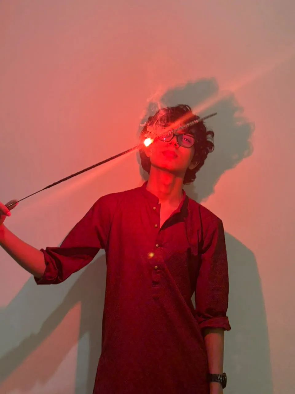 Aayan in a red kurta holding a sparkler, lit in red