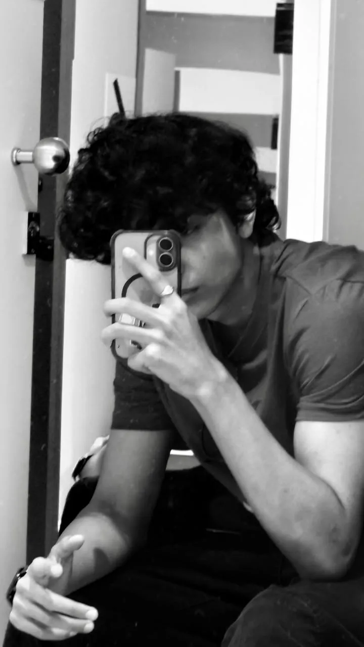 Black-and-white mirror selfie, phone covering Aayan's face