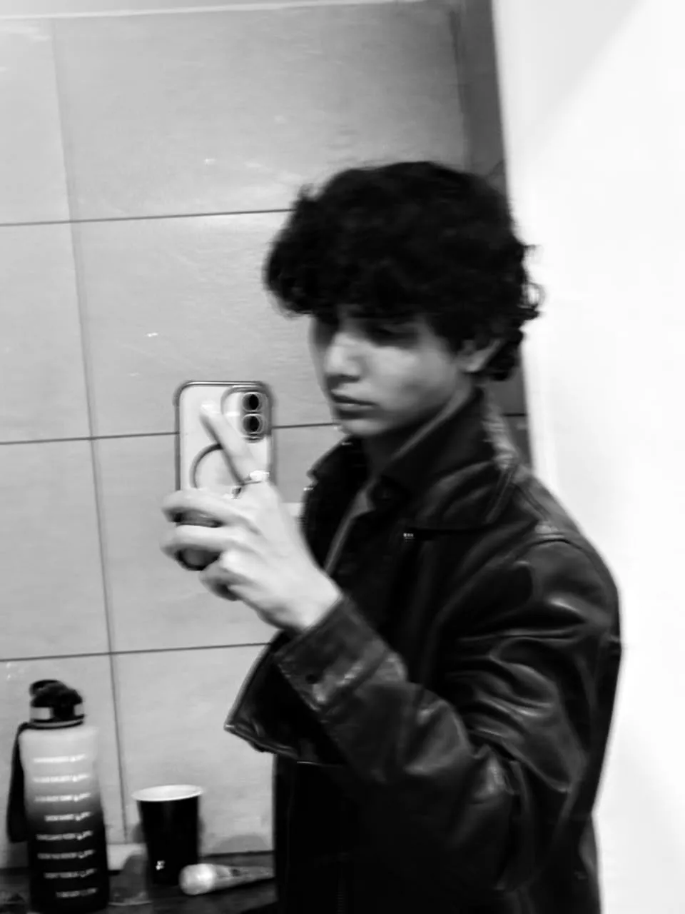 Black-and-white mirror selfie of Aayan in a leather jacket