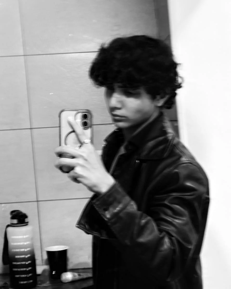 Black-and-white mirror selfie of Aayan in a leather jacket